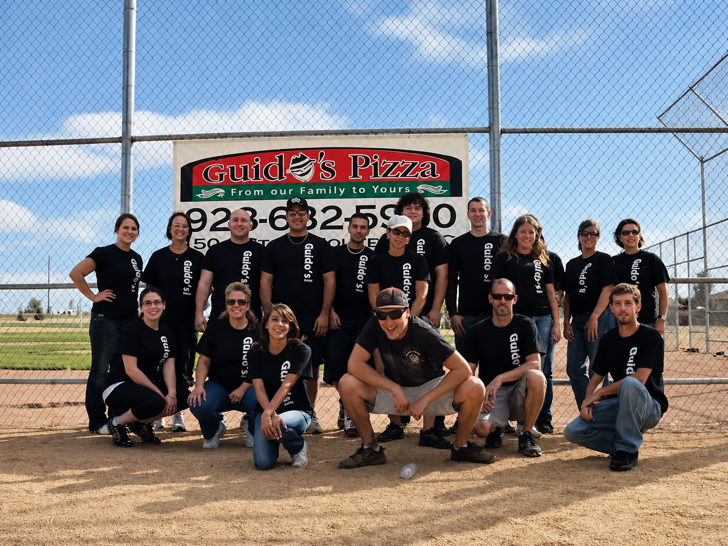 The Guido's Pizza team in front of the Guido's Pizza sign